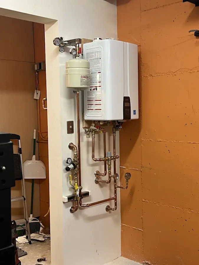 Plumbing technician inspecting water heater connections in Audubon